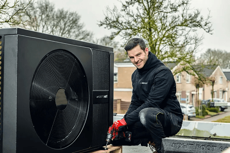 Monteur installeert een AeroWatt-buitenunit op een plat dak